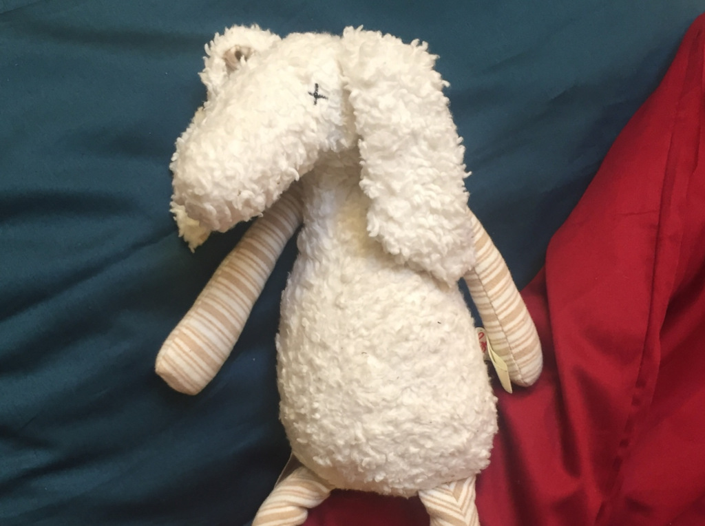 Stofftier Schaf auf buntem Kissen